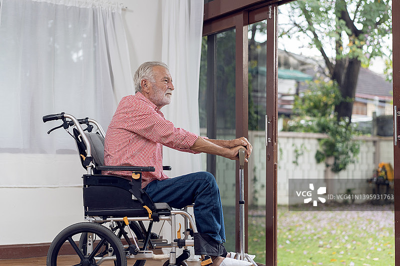坐在轮椅上，望向窗外的老年男人图片素材