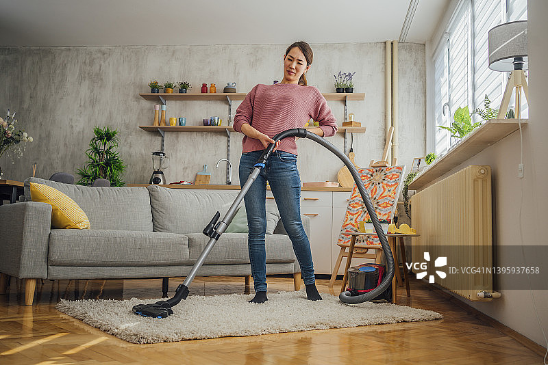 背痛时吸尘的妇女图片素材