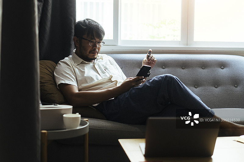 充满积极情绪的亚洲年轻人专注于使用手机和信用卡在家进行网上购物，居家生活图片素材