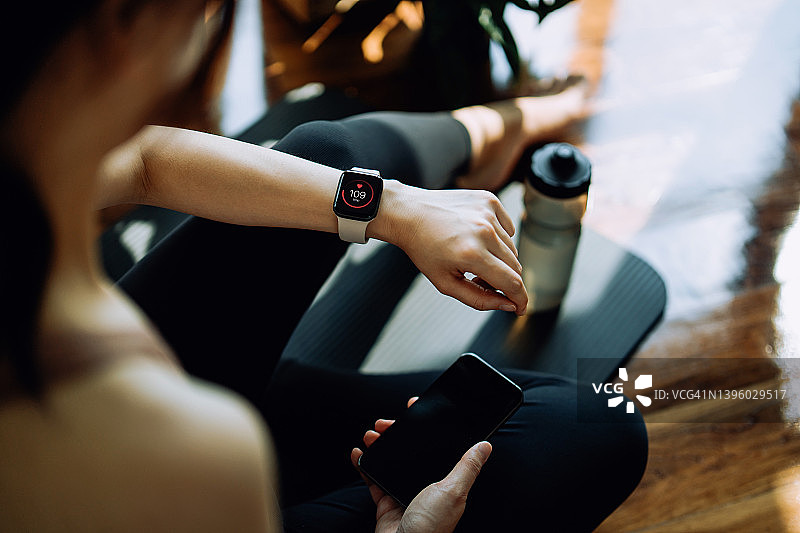 亚洲女人在家用智能手表健身，记录健康数据。图片素材