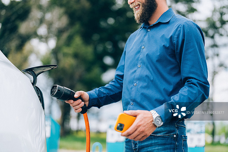 男人给电动汽车充电图片素材