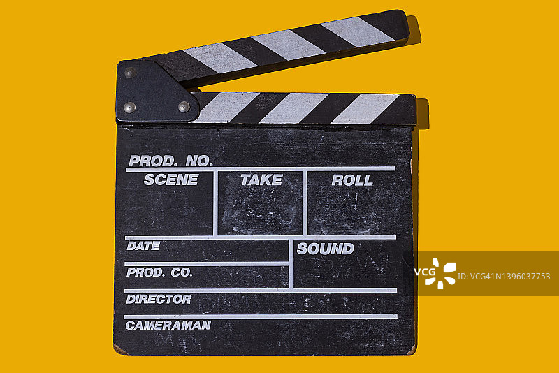 黄色背景下的老式木制电影场记板，硬阴影。电影行业、电影、娱乐和好莱坞概念图片素材