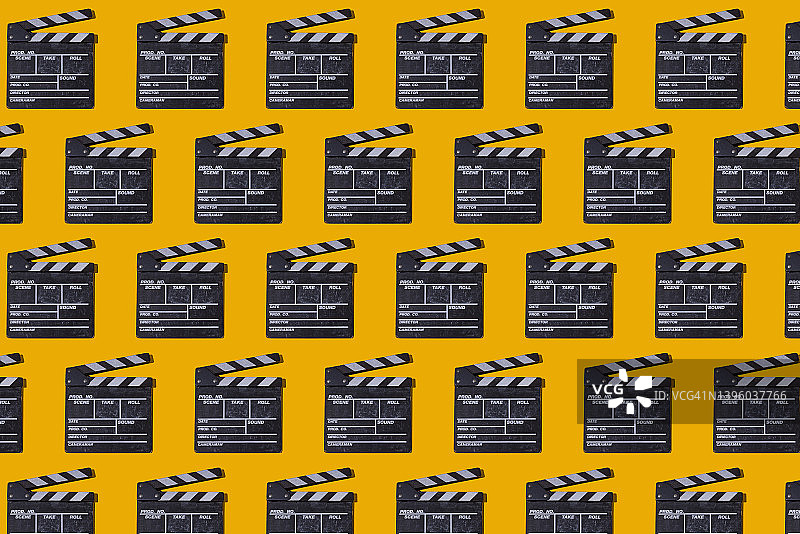 黄色背景上带有硬阴影的木制旧电影场记板图案。电影行业、电影院、娱乐和好莱坞概念图片素材