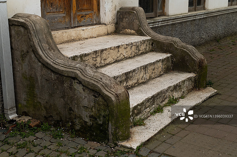 旧公寓楼的混凝土楼梯和木门入口：破旧废弃建筑的一部分图片素材