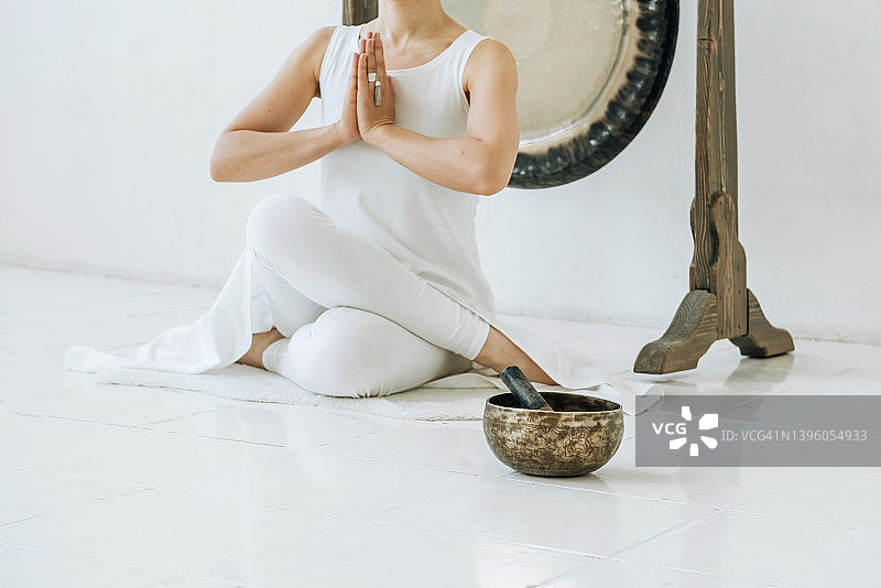 练习瑜伽时冥想的匿名瑜伽女人和颂钵图片素材