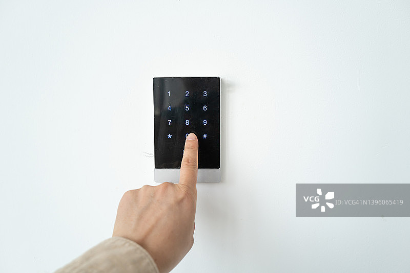 男子正在按白色墙上的密码锁图片素材
