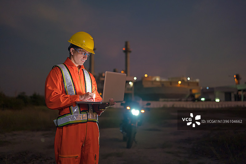 男人工程师在工业区发电站现场使用笔记本电脑工作到深夜图片素材