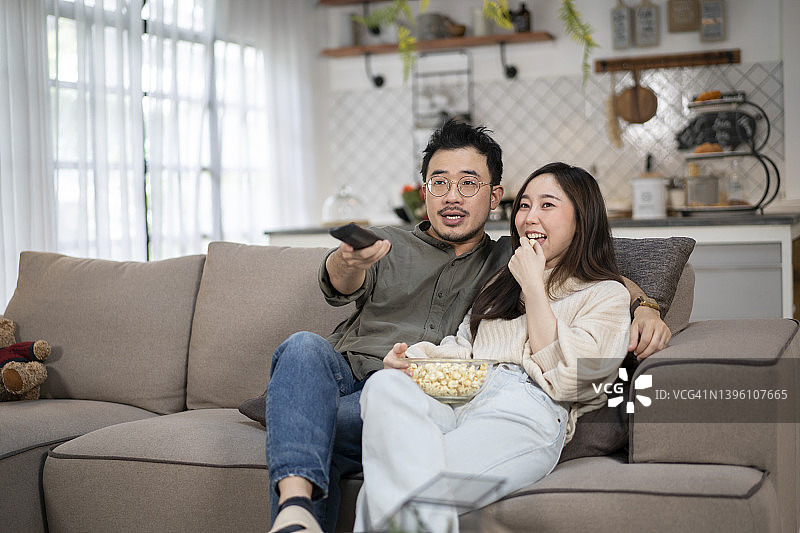 快乐的年轻夫妇在客厅看电视图片素材