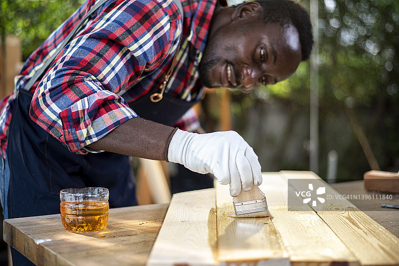 木匠在木地板或他的工件上刷漆图片素材