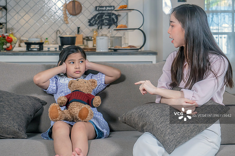 年轻的母亲在客厅里责骂女儿图片素材