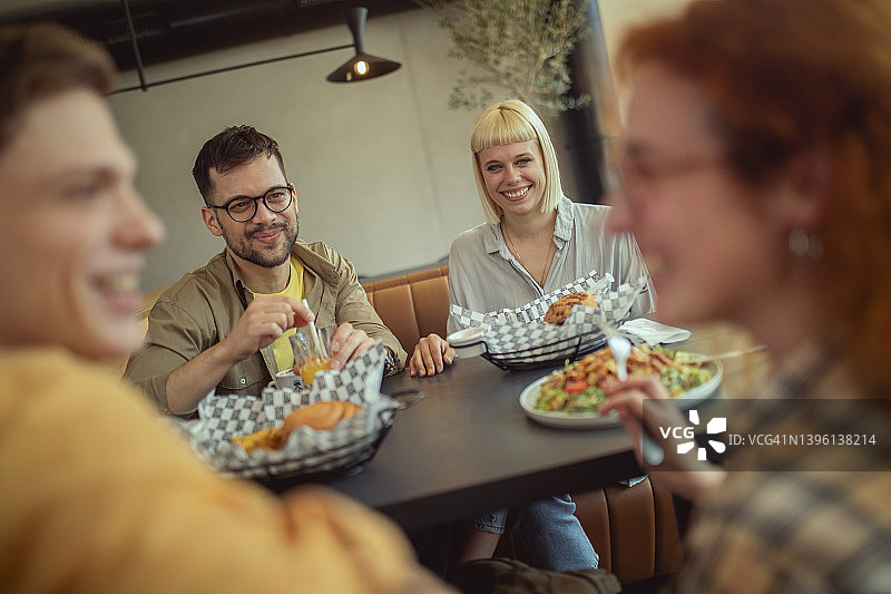 年轻人在快餐店享受不健康的食物图片素材