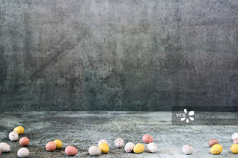 巧克力迷你复活节彩蛋特写，散落在灰色纹理表面，有复制空间图片素材
