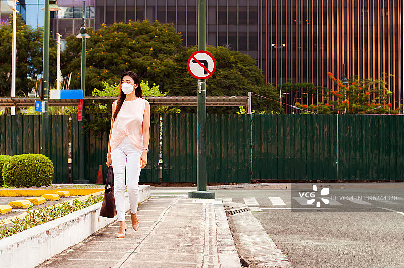 戴口罩的东南亚女性在城市中步行上班图片素材