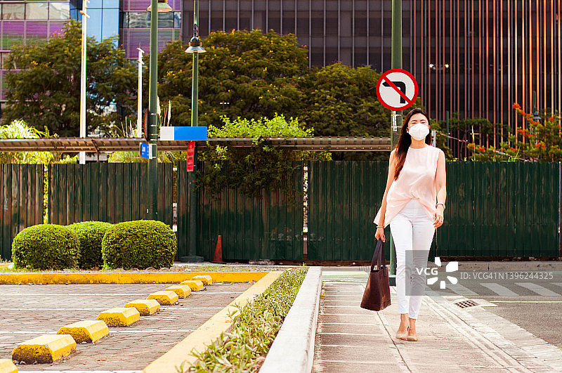 戴口罩的东南亚女性在城市中步行上班图片素材