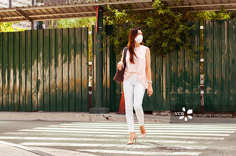 戴口罩的东南亚女性在城市中步行上班图片素材