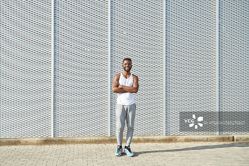 在阳光明媚的夏日，站在有纹理墙壁前的非裔美国人图片素材
