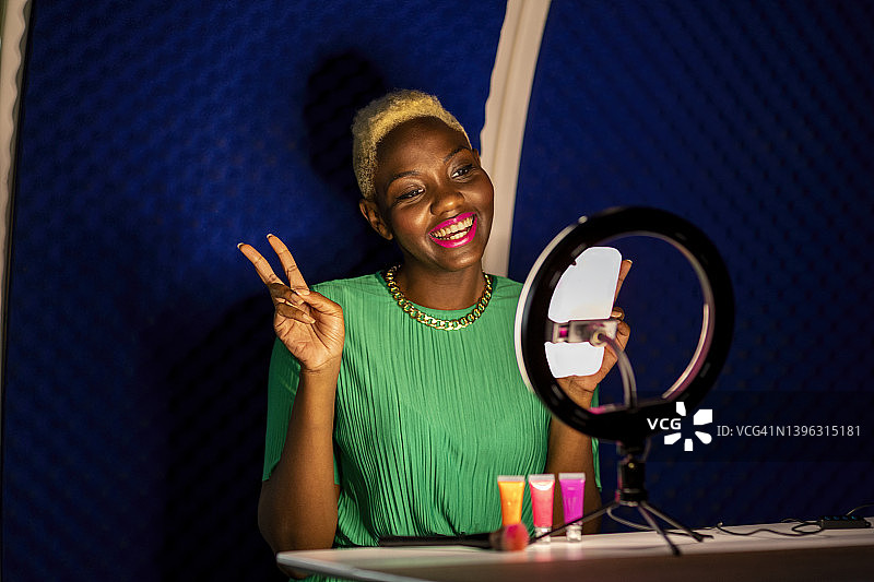 女人对着智能手机微笑，在网上录制Vlog图片素材