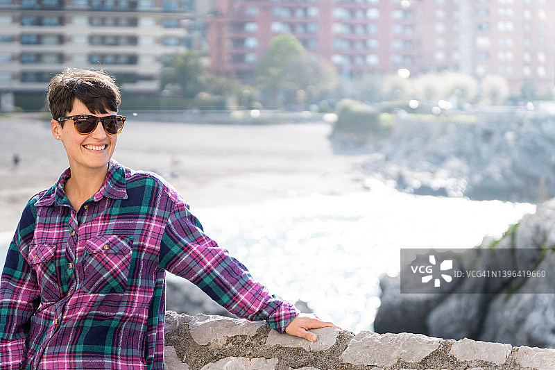 美丽海景沙滩背景下戴太阳镜的短发微笑青年女人人像图片素材