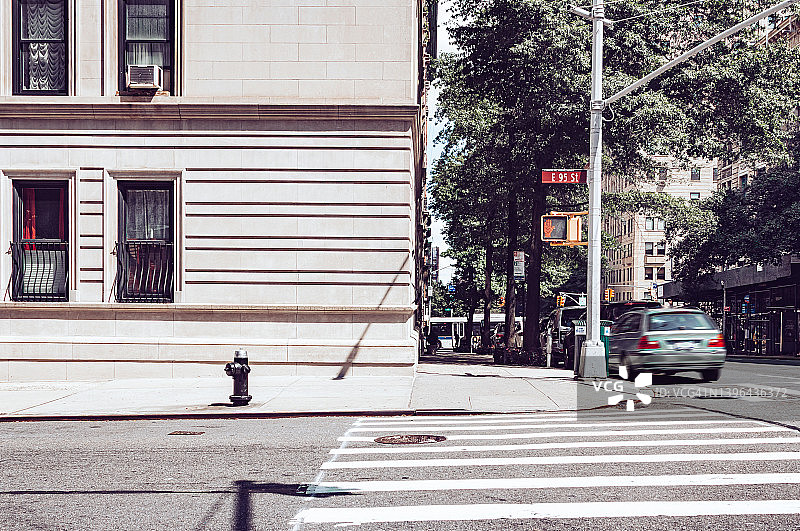 曼哈顿中城东55街街角阳光明媚的午间人行横道红灯，新古典主义建筑，汽车模糊运动图片素材