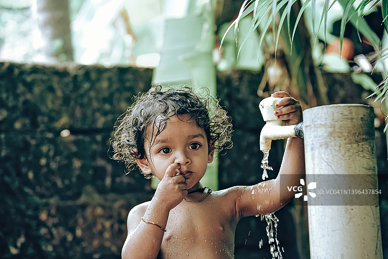 在自来水下洗澡的小男孩图片素材