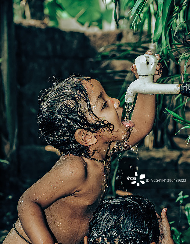 在自来水下洗澡的小男孩图片素材