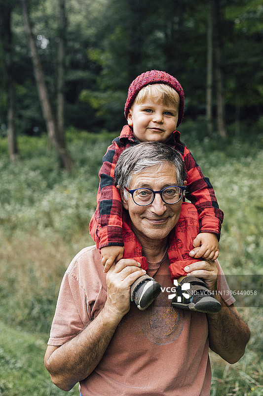 微笑的年长男人肩上扛着孙子图片素材