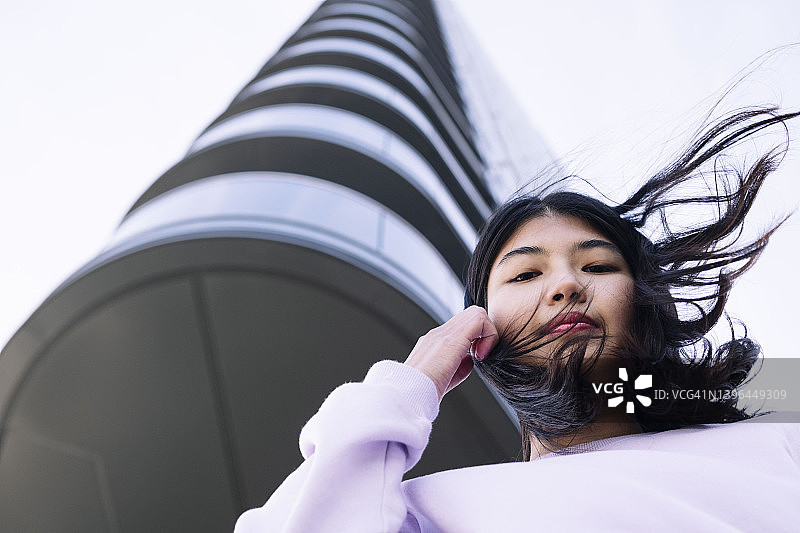 头发蓬乱的年轻女人站在摩天大楼前图片素材