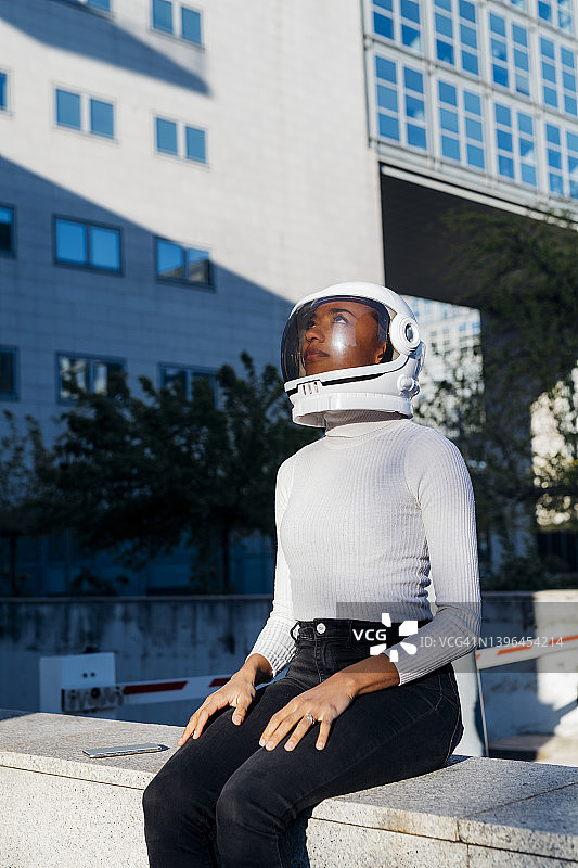 沉思的女商人头戴太空头盔坐在墙边图片素材