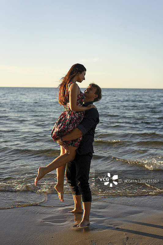 阳光明媚，男友在海滩上托举女友图片素材