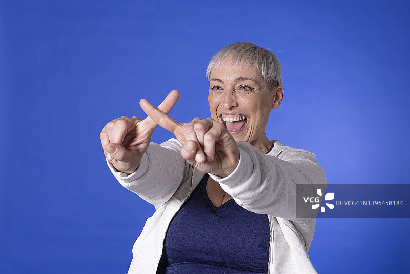 快乐的女人用手指对着蓝色背景做出十字标记图片素材