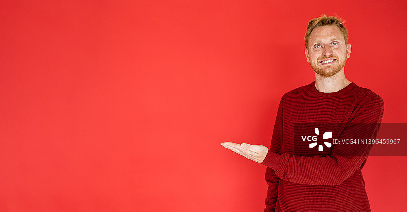 在红色背景上展示空白区域的年轻男子图片素材