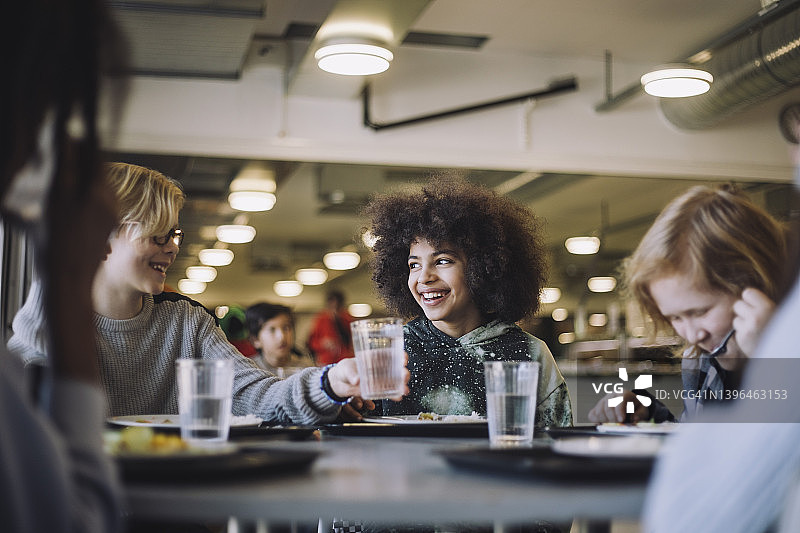午休时男孩递给朋友一杯水图片素材