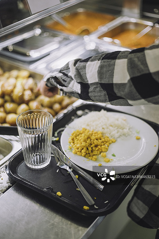 午休期间，男孩在食品吧的盘子里续食物图片素材