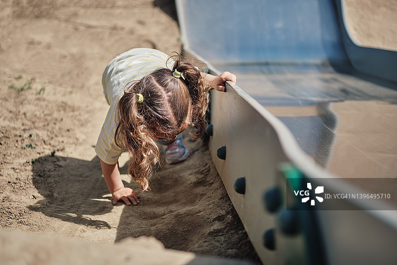 在滑梯旁的沙坡上玩耍的女孩图片素材