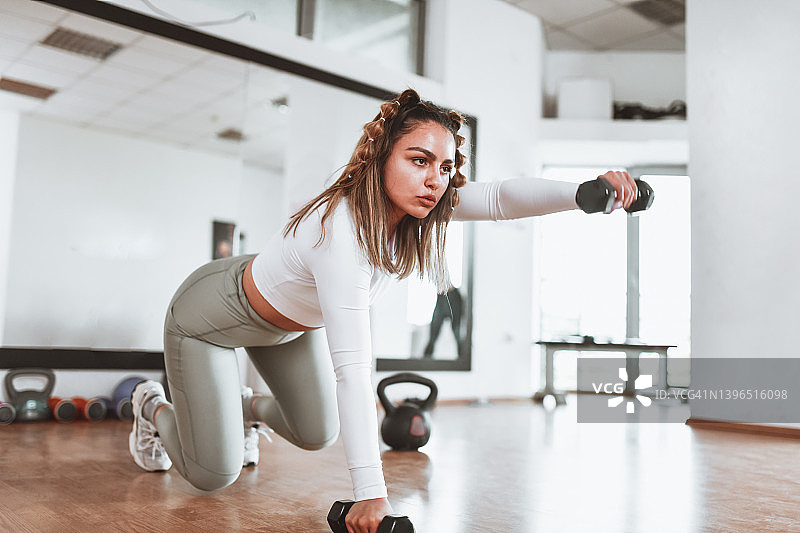 女运动员在健身房进行哑铃锻炼图片素材
