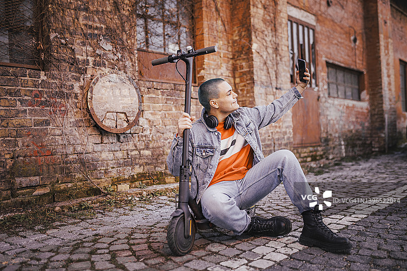 在电动滑板车上使用智能手机的年轻男人：科技生态出行概念图片素材