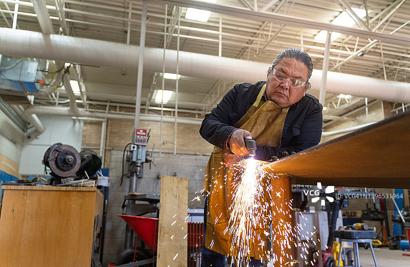 在犹他州纪念碑谷的工作室内使用金属切割器的男人图片素材