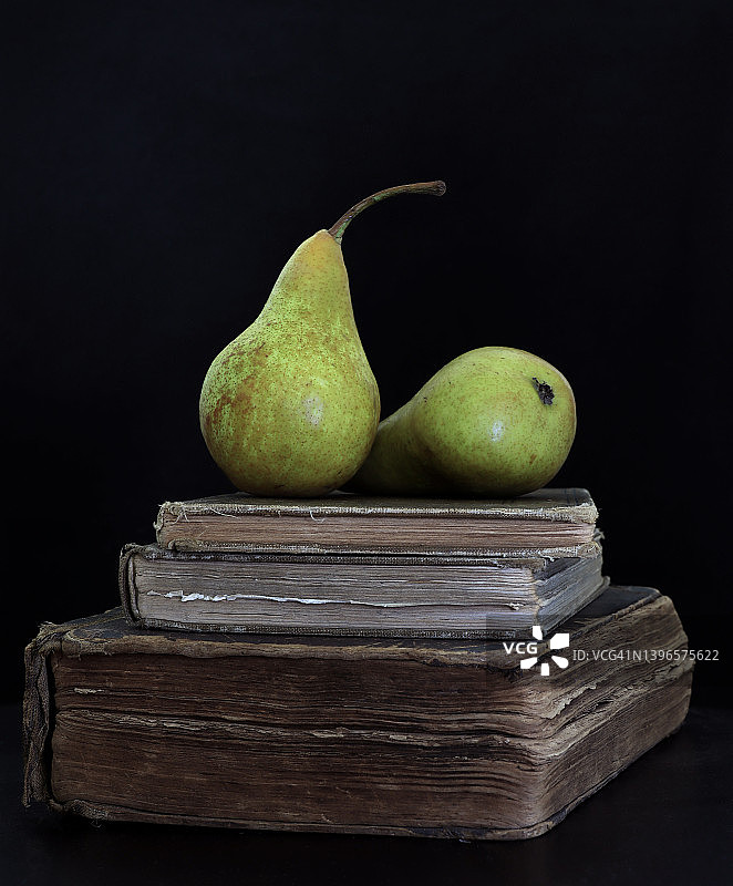 黑色背景下的旧书上的两个梨图片素材