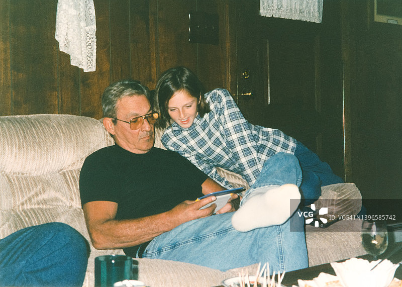 90年代复古家庭照：父女在家用电子设备上玩游戏图片素材