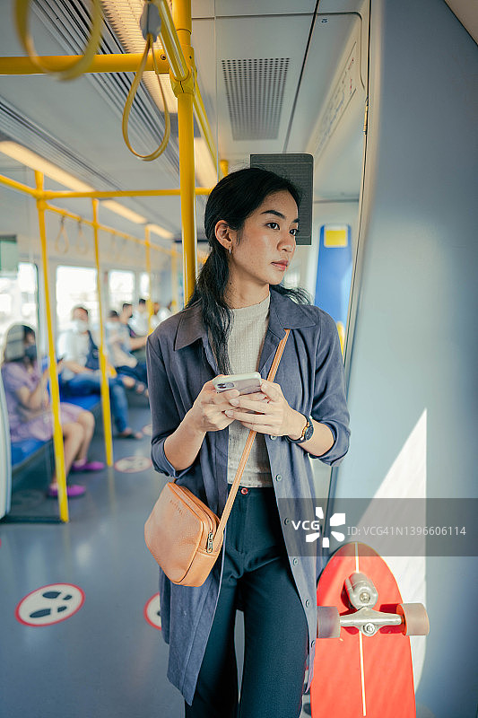 亚洲人在电动火车上使用智能手机图片素材