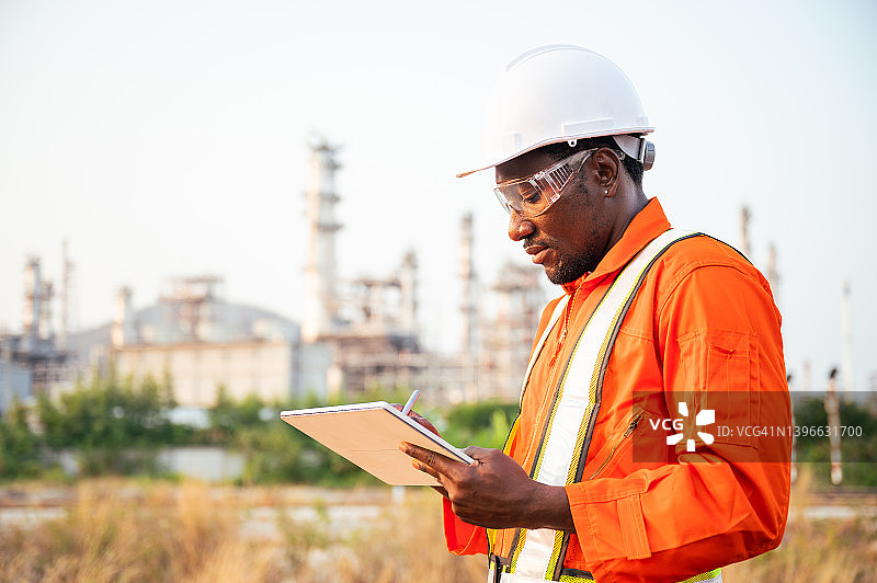 在工业区使用数字平板电脑审查建筑项目的非洲建筑工程师图片素材