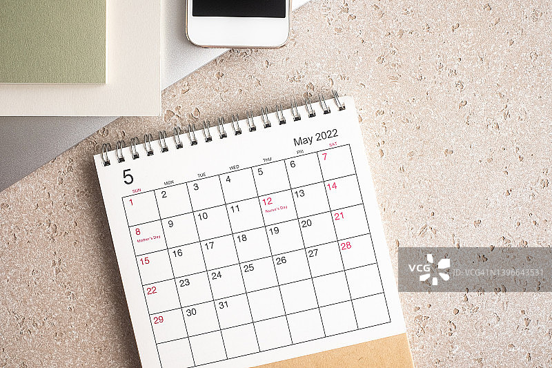 办公室桌子和文具，配有笔记本电脑、记事本、智能手机和2022年5月日历，混凝土背景，顶部视图，带复制空间图片素材