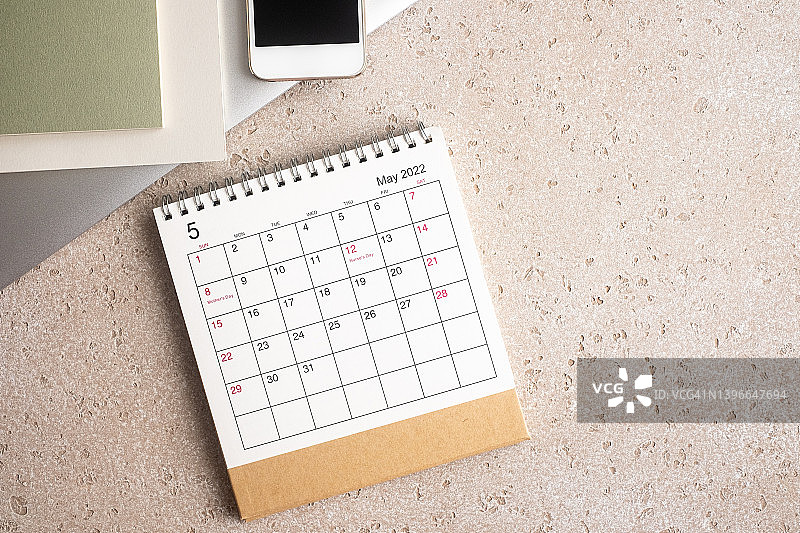 办公室桌子和文具，配有笔记本电脑、记事本、智能手机和2022年5月日历，混凝土背景，顶部视图，带复制空间图片素材