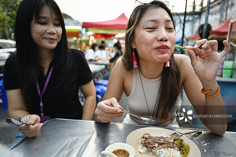 女人在清迈街头小吃摊吃辣椒图片素材