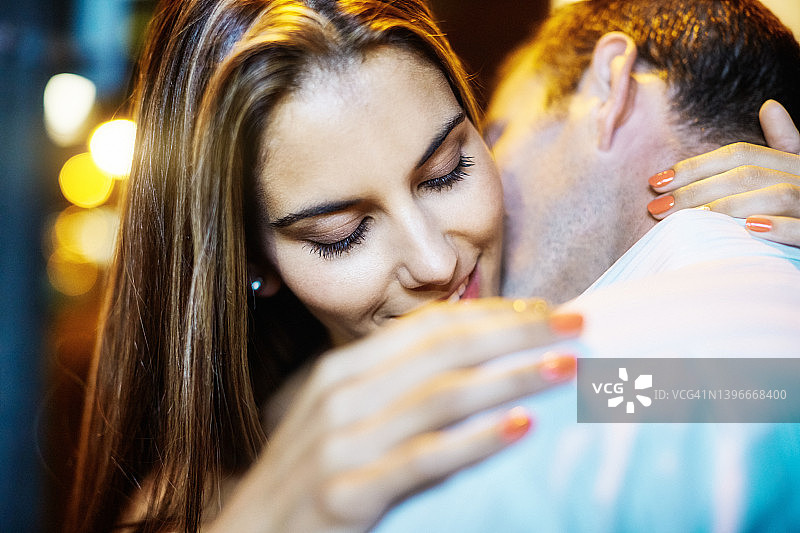 年轻情侣在夜晚的城市街道拥抱图片素材