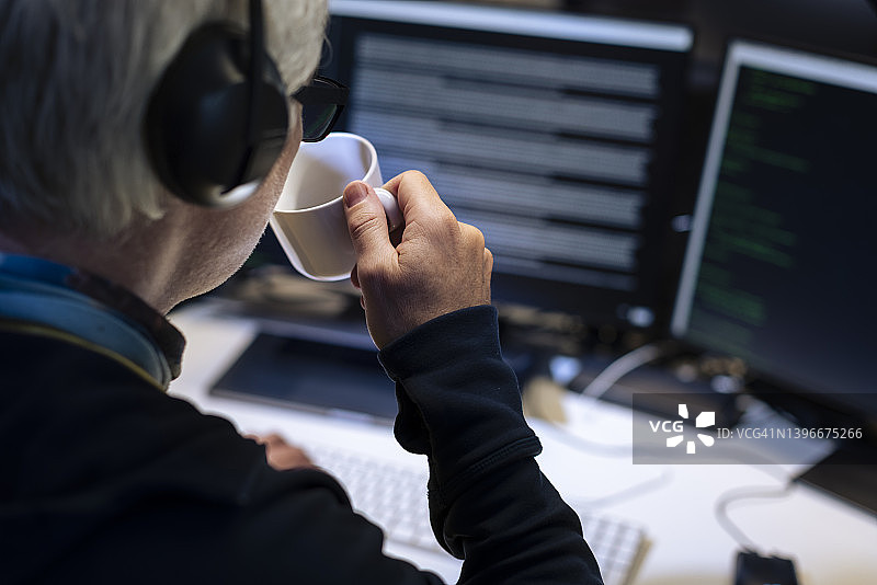 男程序员使用电脑喝着马克杯图片素材