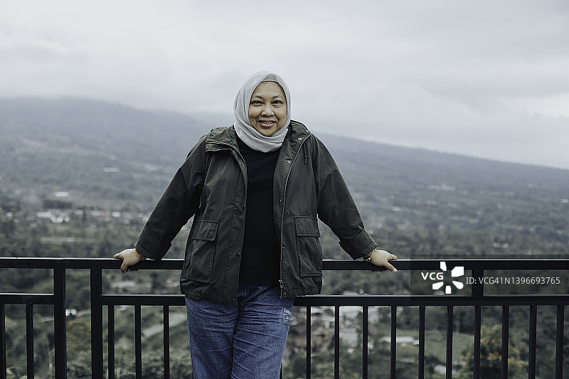 在日惹附近眺望默拉皮火山的亚洲穆斯林女人图片素材