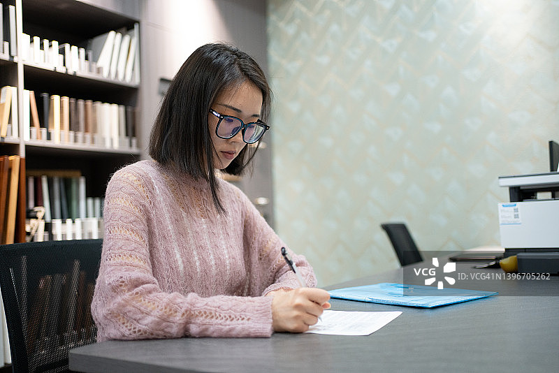 年轻的亚洲女性签署文件图片素材