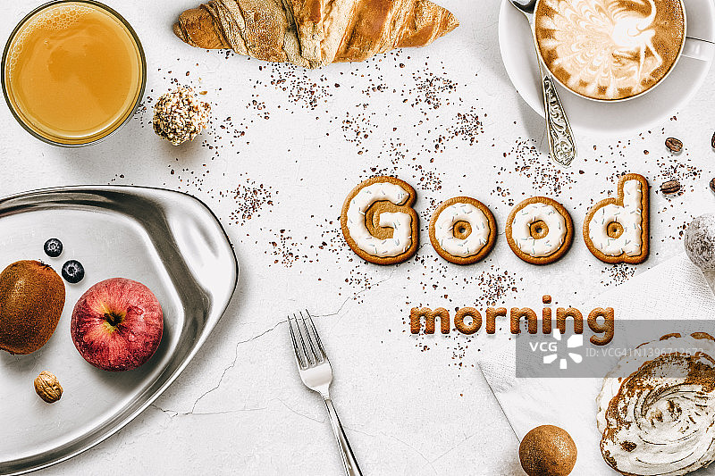 俯视质朴的木制表面，配有咖啡杯和茶。早安留言。早餐图片素材