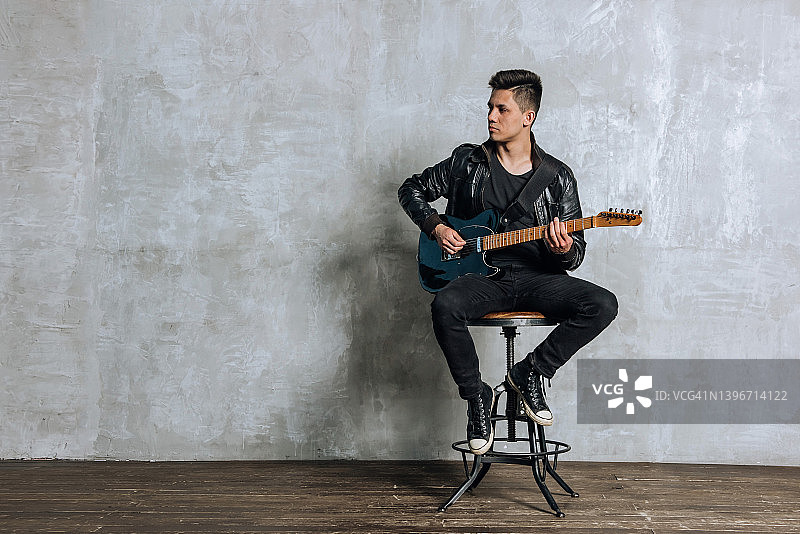 摇滚音乐会上坐在椅子上弹吉他的男音乐人图片素材